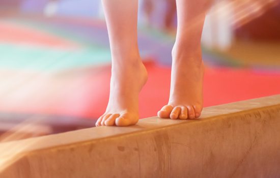 Young female barefoot on balance beam gymnastic balance practicing background